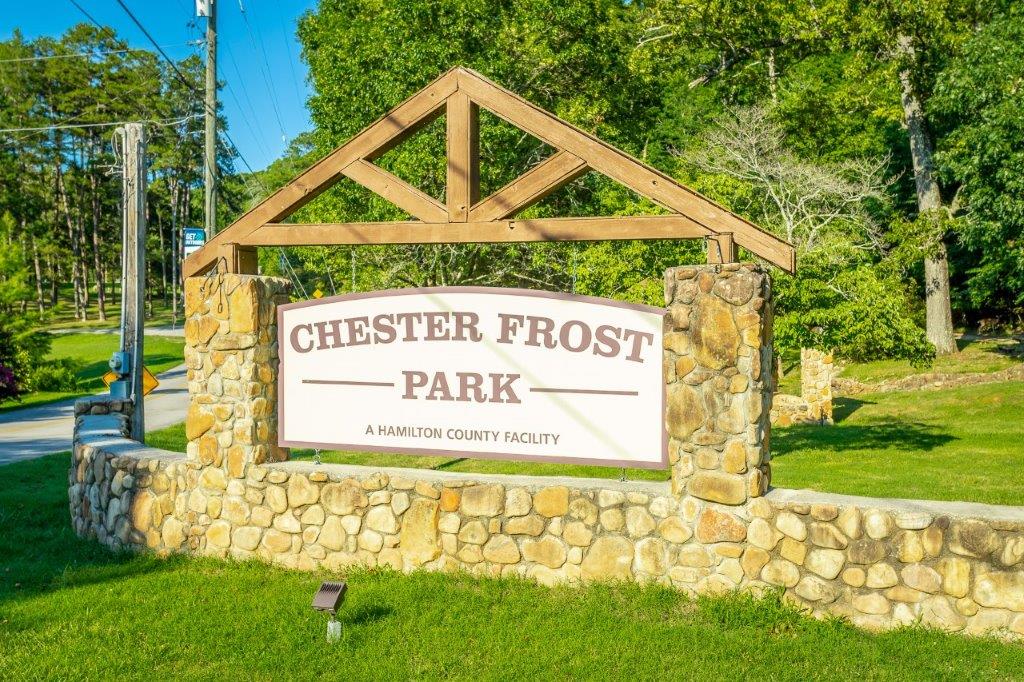 Sign of Chester Frost Park in Hixson, Tn. surrounded by stone, green grass and trees