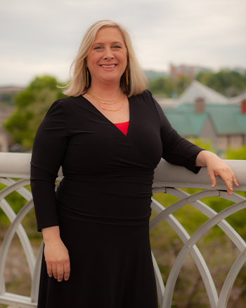 Photo of Brandie Driskell, the Director of Client Services whom is committed to exceptional service. Standing on a bridge with downtown Chattanooga behind her.