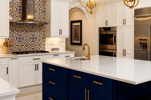 Photo of beautiful kitchen with center island and blue cabinets.  White cabinets everywhere else.  Gold trim, double oven and mosaic ceramic tile up the wall behind the stove.  This is a great example of the top home features buyers are looking for in 2023
