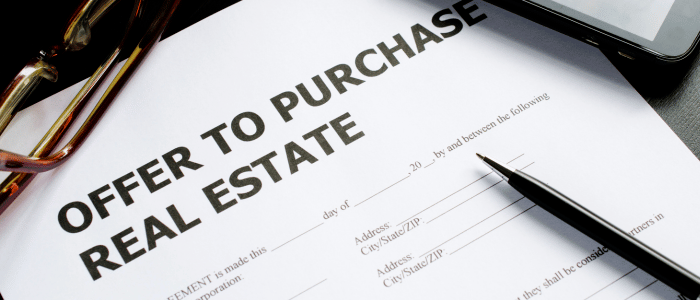 Photo of an offer to purchase real estate with glasses and a pen to make notes located below offers and negotiations on the page and across the whole page.