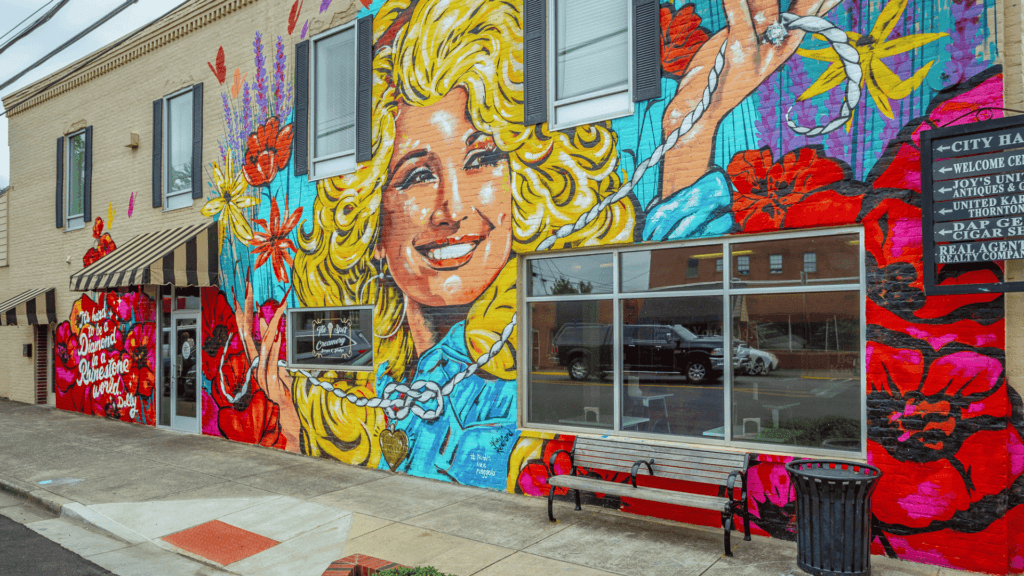 Photo of the Dolly Parton mural in downtown Ringgold, GA.   Young Dolly Parton face with blond curled hair wither her famous quote it's hard to be pearls in a rhinestone world. 