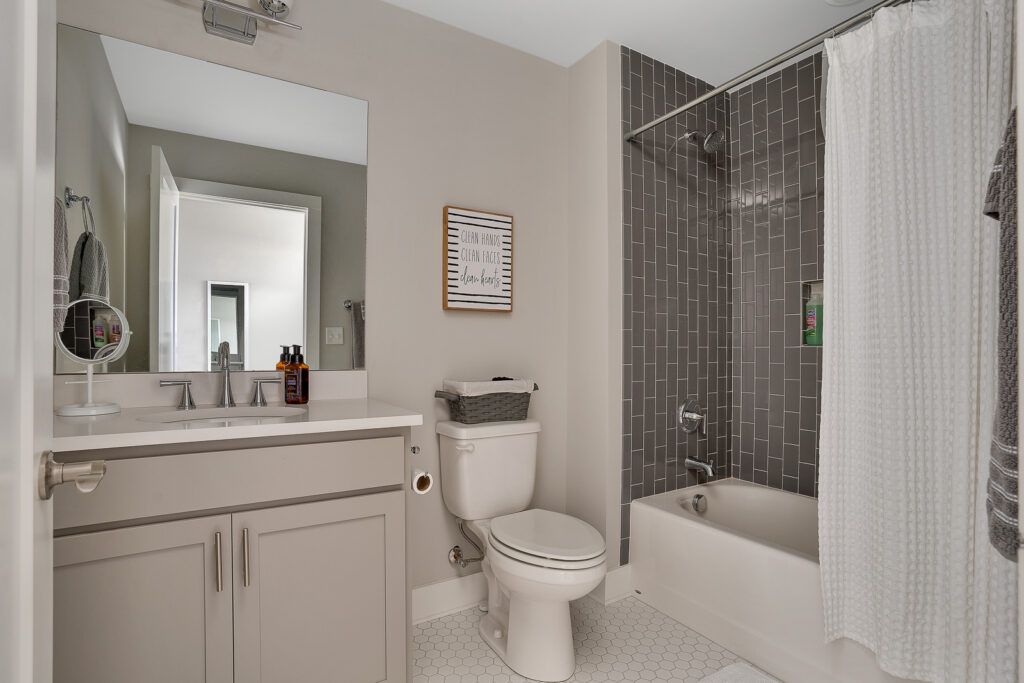 Primary's bathroom for 3059 St. Elmo Ave with full tub and grey subway tile walls 1 sink vanity and beige walls.