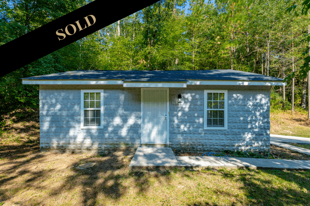 Sold Picture of the front of 2711 Banks Road. 1 story tiny home with grey block.