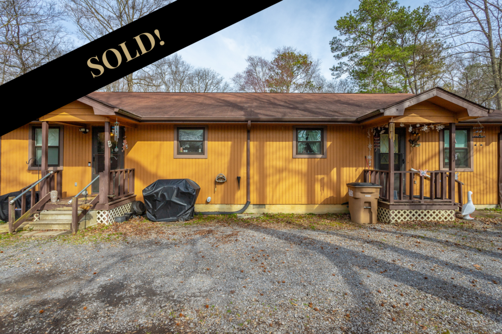 Front of 315 Old Lake Road a 2 unit duplex with mustard colored siding 1 story and brown shingled roof. SOLD