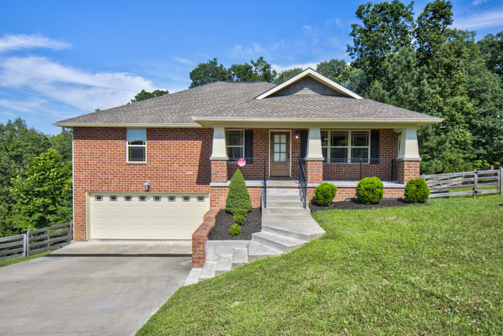 Front of 6253 River Stream Drive a 1 story brick home on a sloping green yard. Double car garage faces front and is located at basement level.