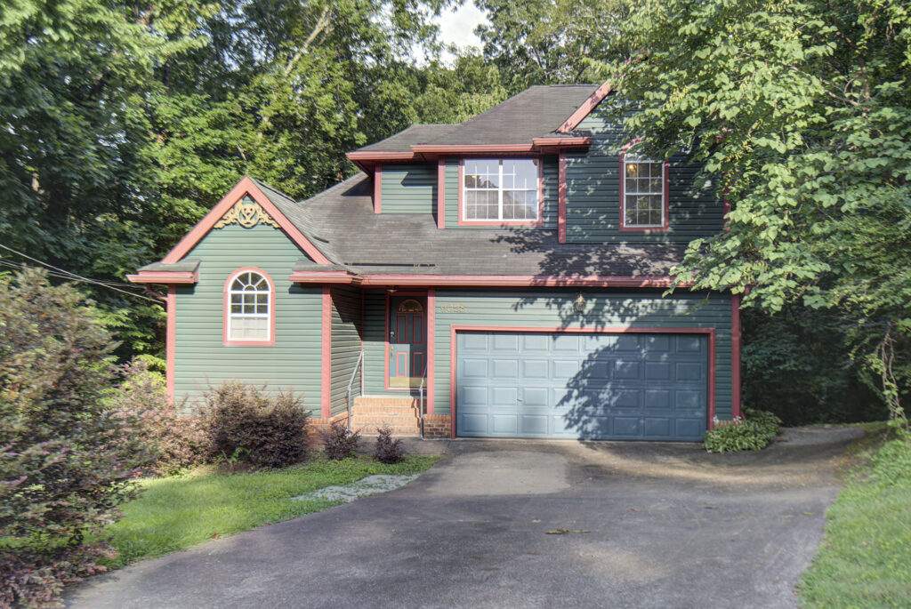 Front of 9028 Warbler Lane a two story home with basement 2 car garage facing front with green siding