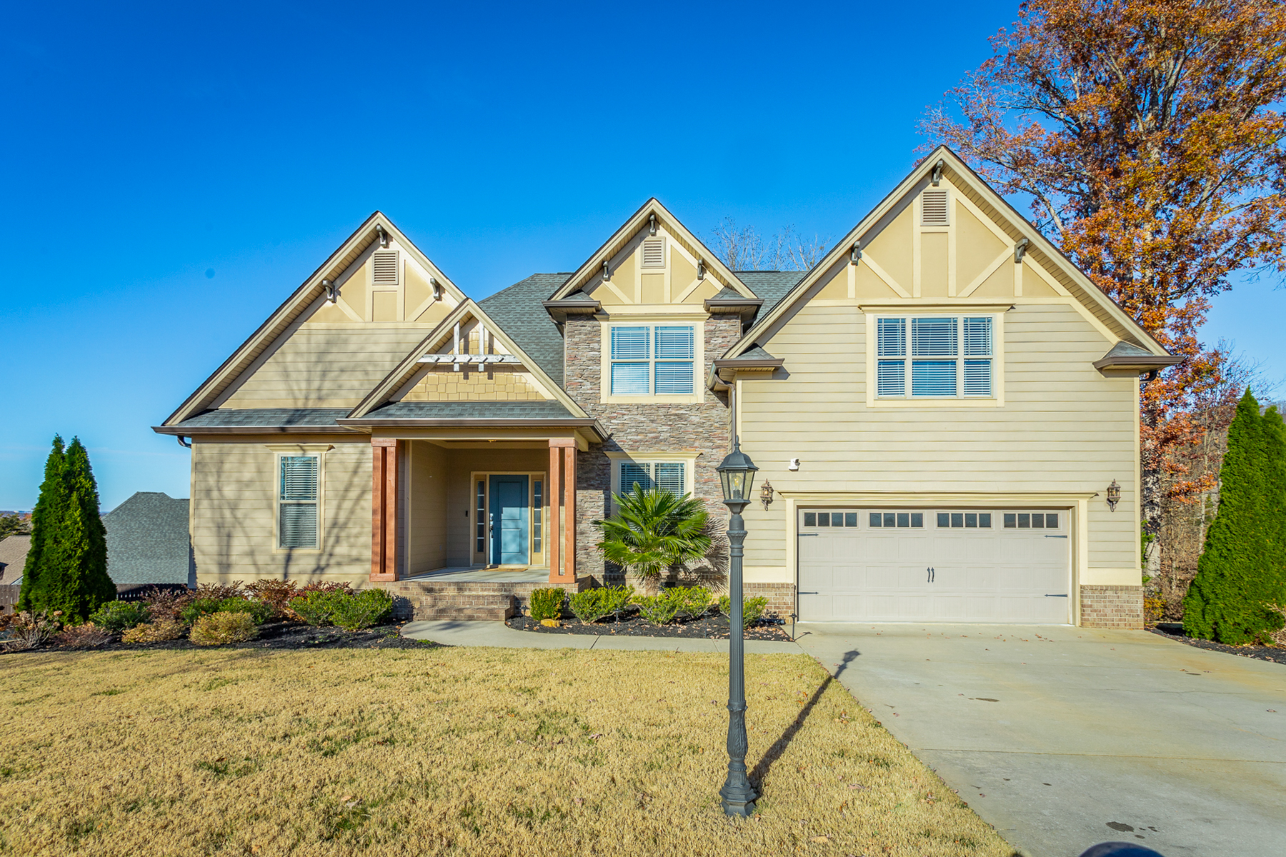 Front of 7538 Sandy Creek Lane a 4 bedroom craftsman style home for sale on level lot with stone facade and yellowish beige siding